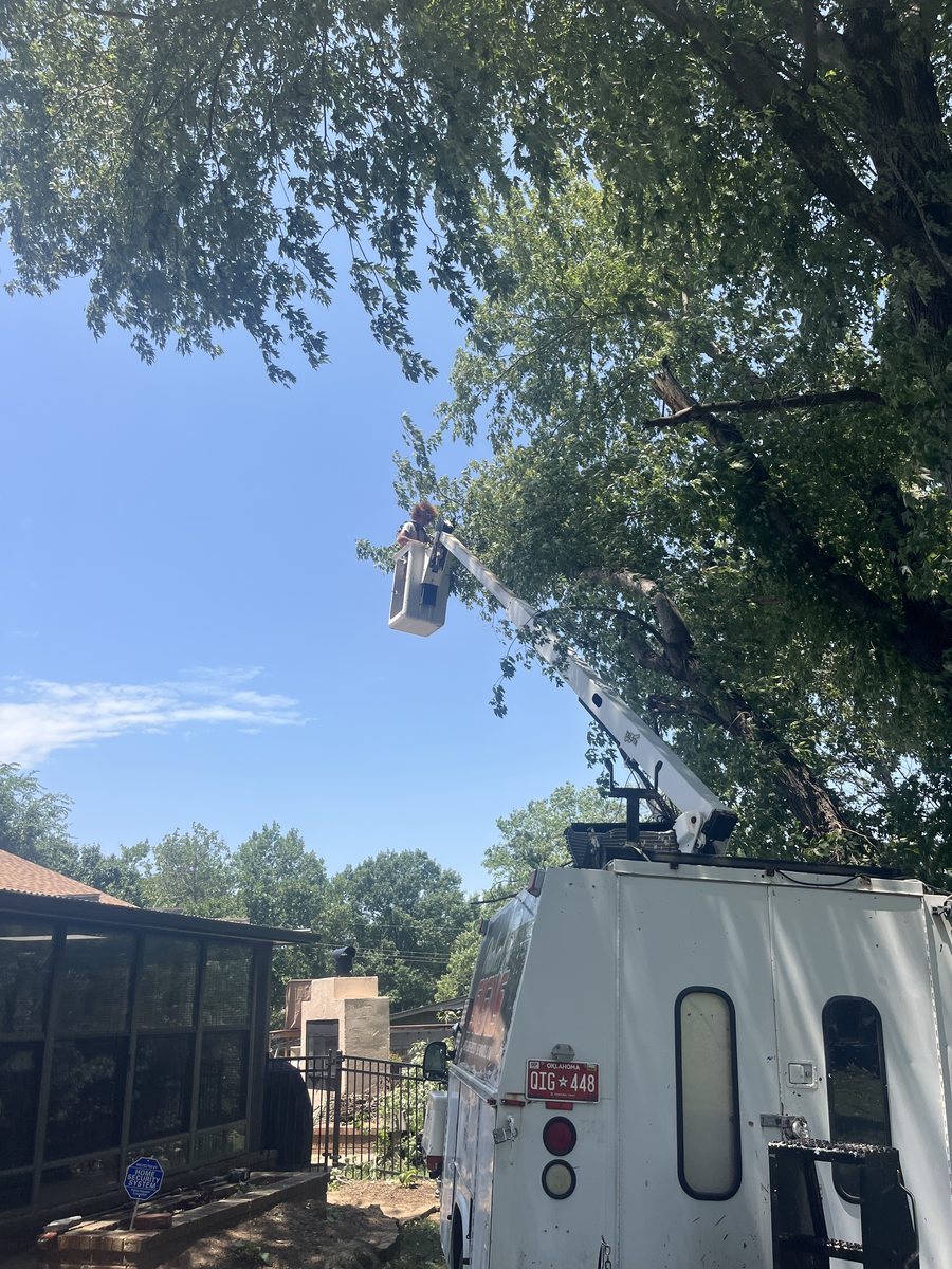 A bucket truck boom extended over a screened porch while crew work below.